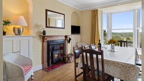 A cozy room with a fireplace, a dining table with chairs, a TV, and a large window with a view.