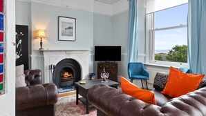 A living room with a fireplace, a television, leather sofas, and a view of the outdoors.