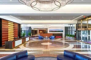Relax in the stylish lobby, featuring a central seating area, reception desk, and polished floor.