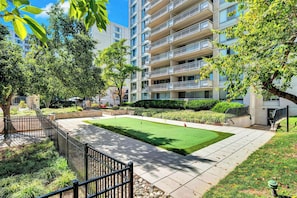 Enjoy leisure activities in a serene courtyard with a putting green and mature trees.