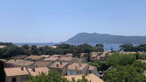 A coastal village with terracotta-roofed houses, a clear blue sky, and a mountain in the background. - Renovated studio, sea view, close to beaches and shops... (ST MANDRIER SUR MER)
