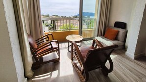 A balcony with a sofa and two chairs, a small round table, and a view of the cityscape. - Renovated studio, sea view, close to beaches and shops... (ST MANDRIER SUR MER)