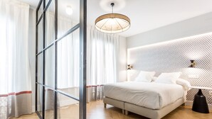 Une chambre d’hôtel moderne dotée d’un grand lit, d’une cloison en verre, d’un plancher en bois et d’un mur à motifs.