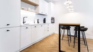 Une cuisine moderne avec des armoires blanches, un plan de travail en bois, un four encastré et des tabourets de bar noirs.