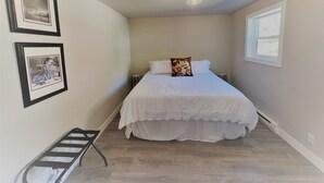 A bedroom with a bed, a nightstand, a window, and framed pictures on the wall. - Outlaw Inn Unit 1. Air conditioning, newly remodeled. Steps from Main Street! (Ouray)