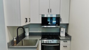 A modern kitchen with light wood cabinets, a stainless steel range, and a built-in microwave. - Outlaw Inn Unit 1. Air conditioning, newly remodeled. Steps from Main Street! (Ouray)