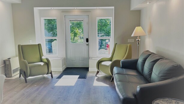 A spacious living room with a grey couch, two armchairs, a small round table, and a door with windows. - Outlaw Inn Unit 1. Air conditioning, newly remodeled. Steps from Main Street! (Ouray)