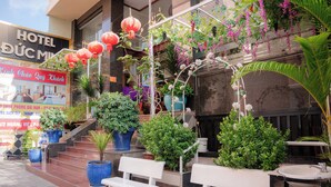 L’entrée d’un hôtel, avec un escalier, des plantes en pot et des sièges à l’extérieur.