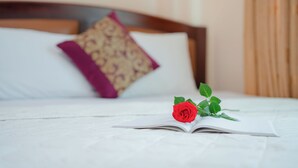 Un lit bien fait, orné d’une seule rose rouge et d’un livre ouvert posé sur le couvre-lit.