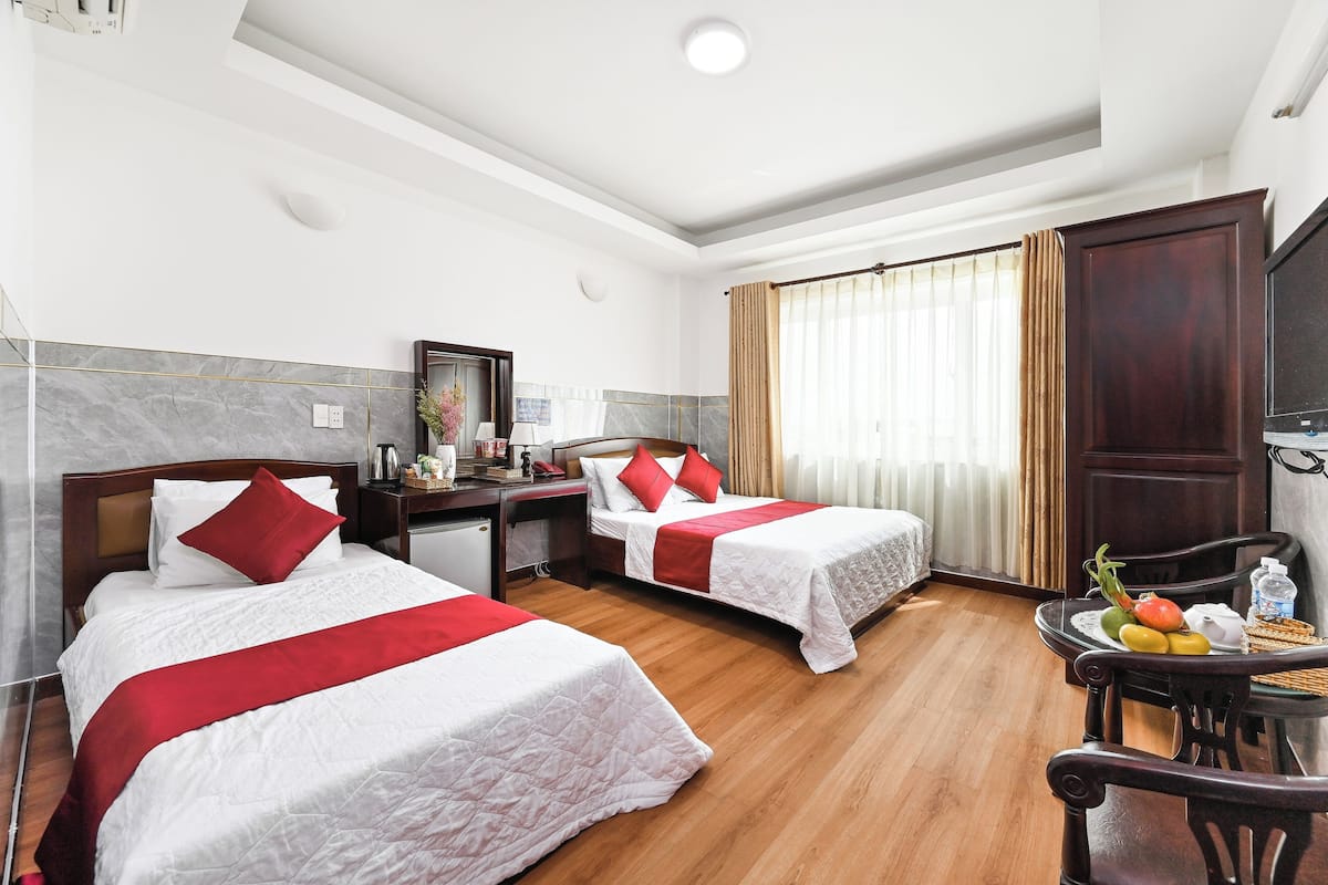 Une chambre d’hôtel avec deux lits, un bureau, une chaise et une table à manger avec des fruits.