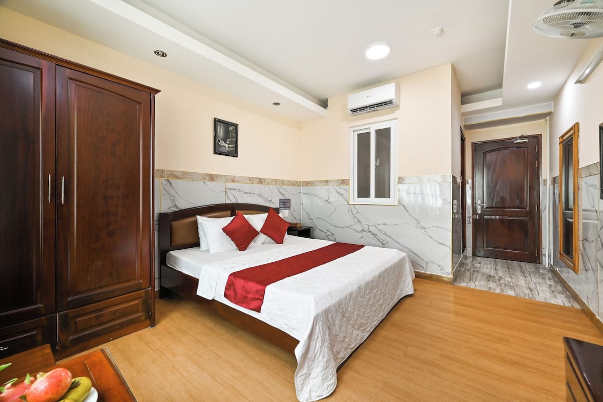 Une chambre à coucher avec un lit, une armoire en bois, un mur en marbre et une porte donnant sur une autre pièce.