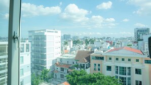 Un paysage urbain avec des bâtiments modernes, un mélange de structures résidentielles et commerciales, et un ciel dégagé parsemé de quelques nuages.