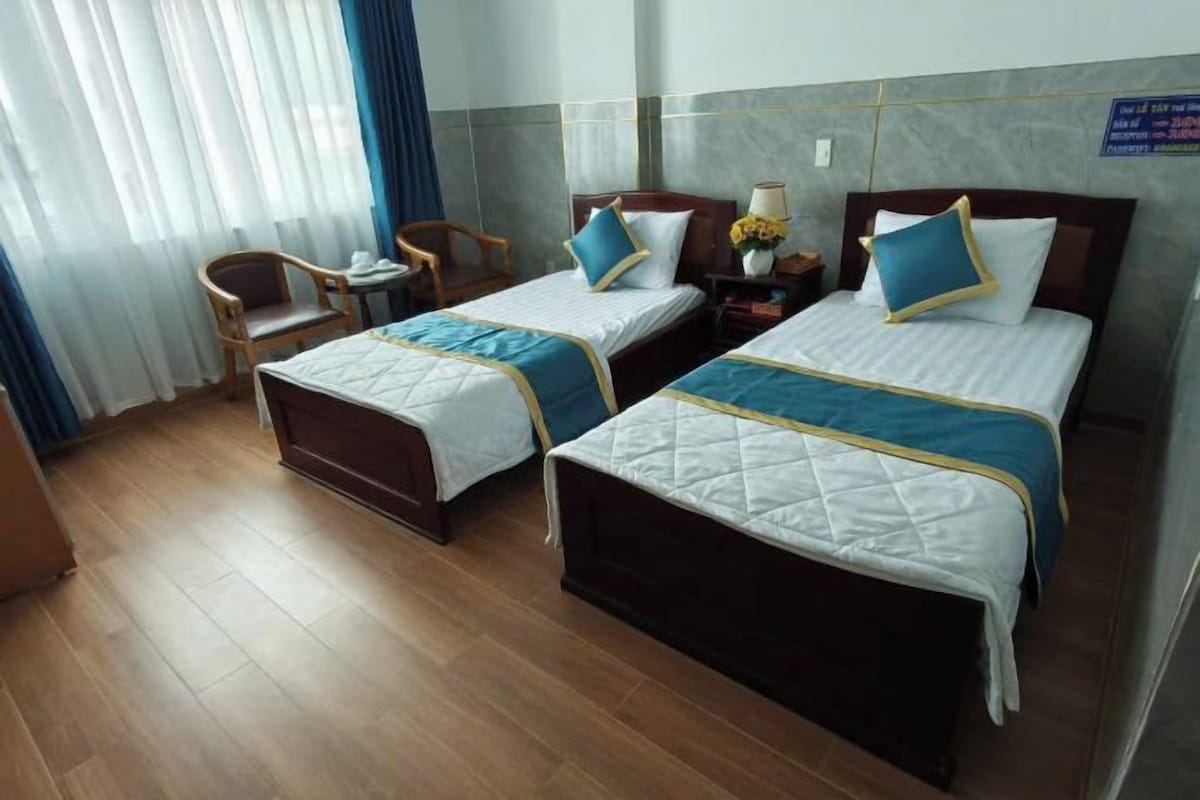 Une chambre d’hôtel avec deux lits, une petite table et une chaise.