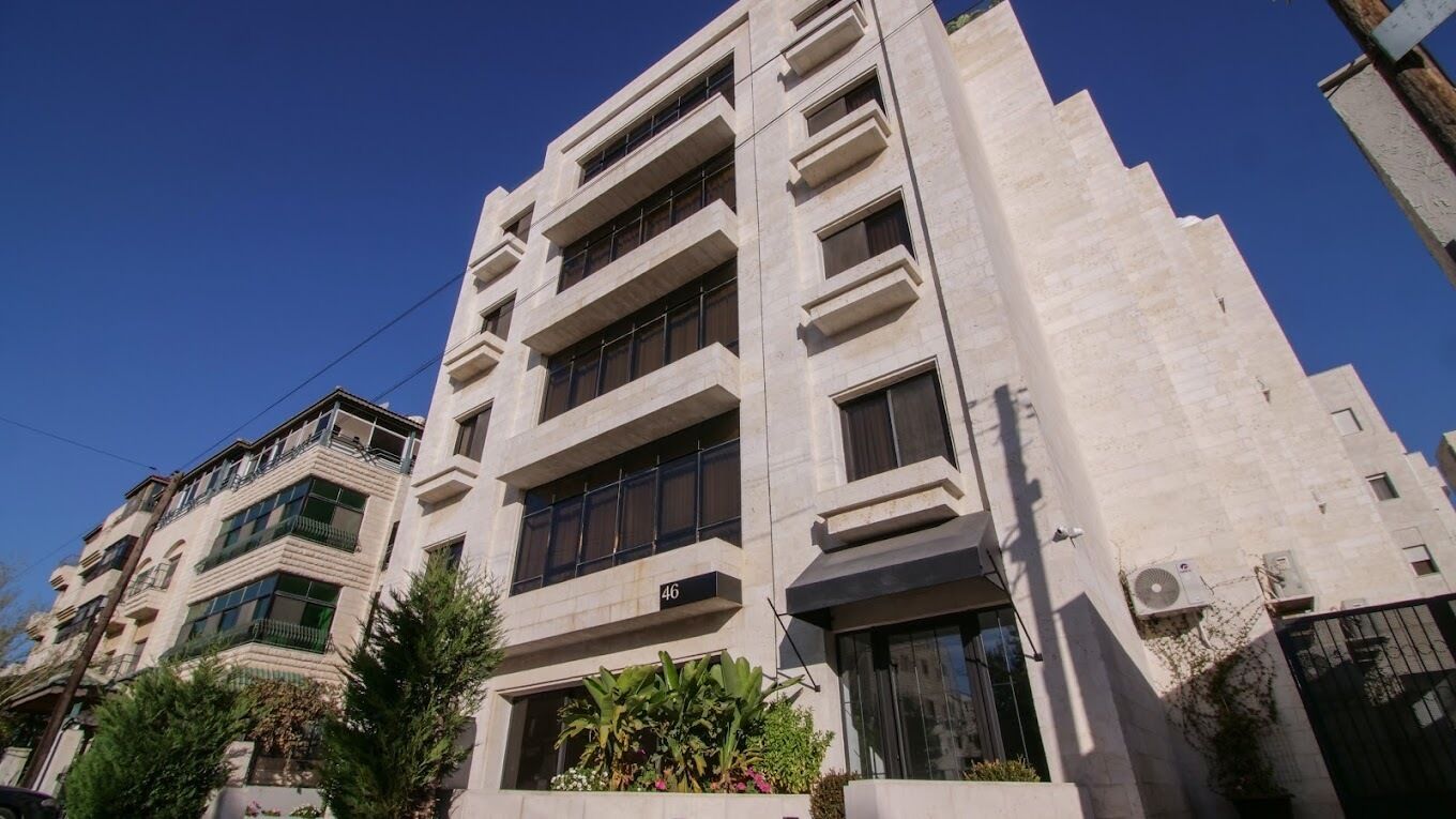 Ein mehrstöckiges Gebäude im modernen Architekturstil, mit Balkonen und großen Fenstern.