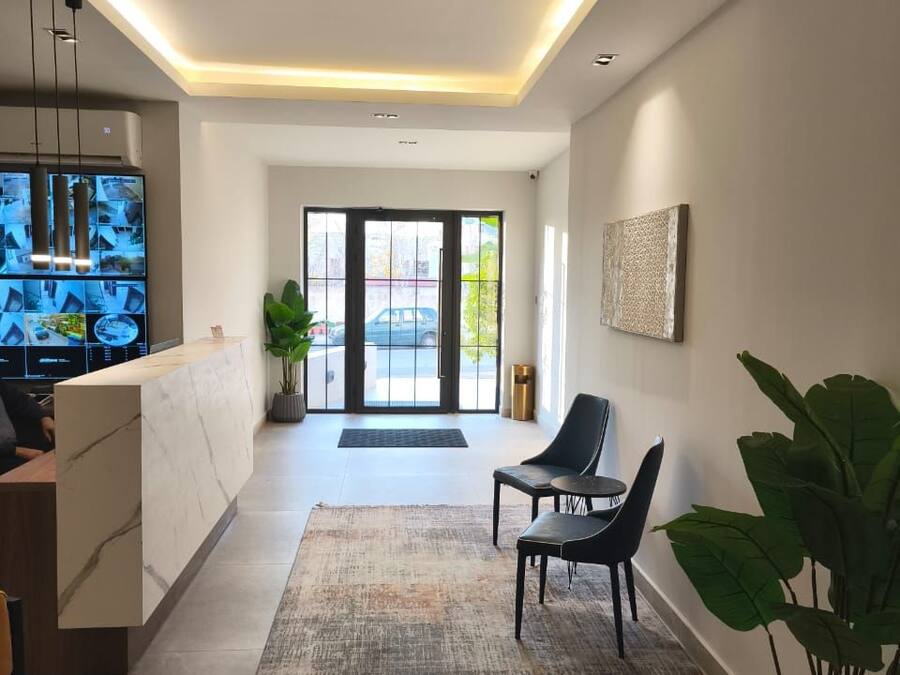 Een moderne hotel lobby met een receptiebalie, een zithoek en grote ramen.