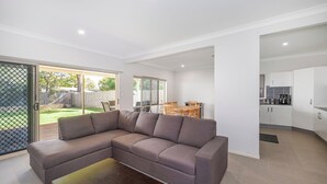 Una sala de estar moderna con un sofá seccional, una mesa de centro y una zona de comedor con mesa y sillas.