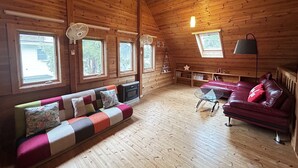En mysig stuga med träpanel, en soffa, en röd läderbäddsoffa och ett litet bord.
