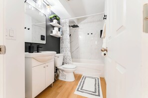 A modern bathroom with a white sink, toilet, and shower.