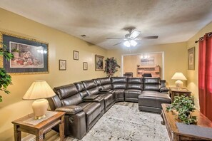 A living room with a sectional sofa, a ceiling fan, and a rug.