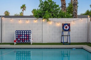 A swimming pool with a white brick wall, string lights, and a target on a stand. - Extravagant Phoenix Retreat|Pool|Gazebo|HeatedPool (Phoenix)