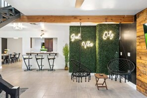 A modern interior with a kitchen area, bar stools, a hanging chair, and a neon sign. - Extravagant Phoenix Retreat|Pool|Gazebo|HeatedPool (Phoenix)