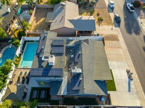 Une propriété résidentielle dotée d’une piscine, de panneaux solaires et d’un patio couvert.