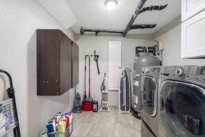 A laundry room with a washing machine, a dryer, and a cabinet. - Extravagant Phoenix Retreat|Pool|Gazebo|HeatedPool (Phoenix)