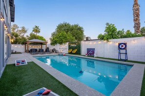 A swimming pool with a surrounding deck, a covered seating area, and a wall with a sign.