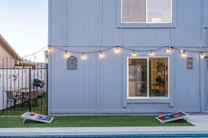 A residential building with a pool, outdoor seating, and string lights.