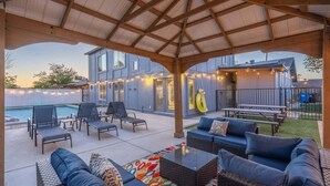 Un espace extérieur aménagé avec une terrasse, des sièges, une piscine et des guirlandes lumineuses.