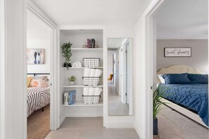 Une chambre à coucher comprenant un lit, une table de chevet, un miroir et une étagère avec des livres et des objets décoratifs.