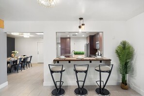 A modern kitchen with a central island, bar stools, and a potted plant. - Extravagant Phoenix Retreat|Pool|Gazebo|HeatedPool (Phoenix)