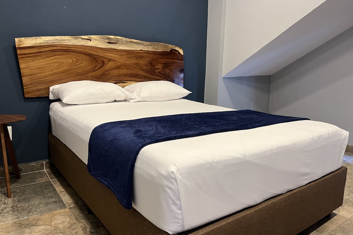 A bed with a wooden headboard, white bedding, and a blue throw blanket.