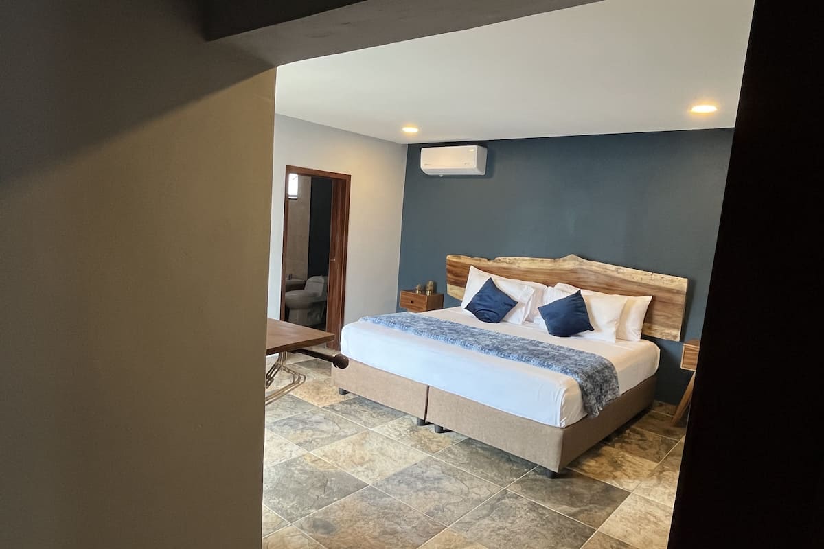 A modern bedroom with a large bed, a wooden headboard, and a small bedside table.