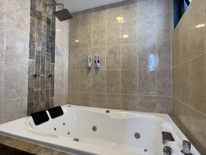 Bathroom features a large bathtub, handheld showerhead, and wall-mounted faucets.