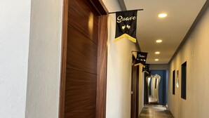 A hallway with wooden doors, black banners with text, and a tiled floor. - Hotel La Bikina (Tequila)