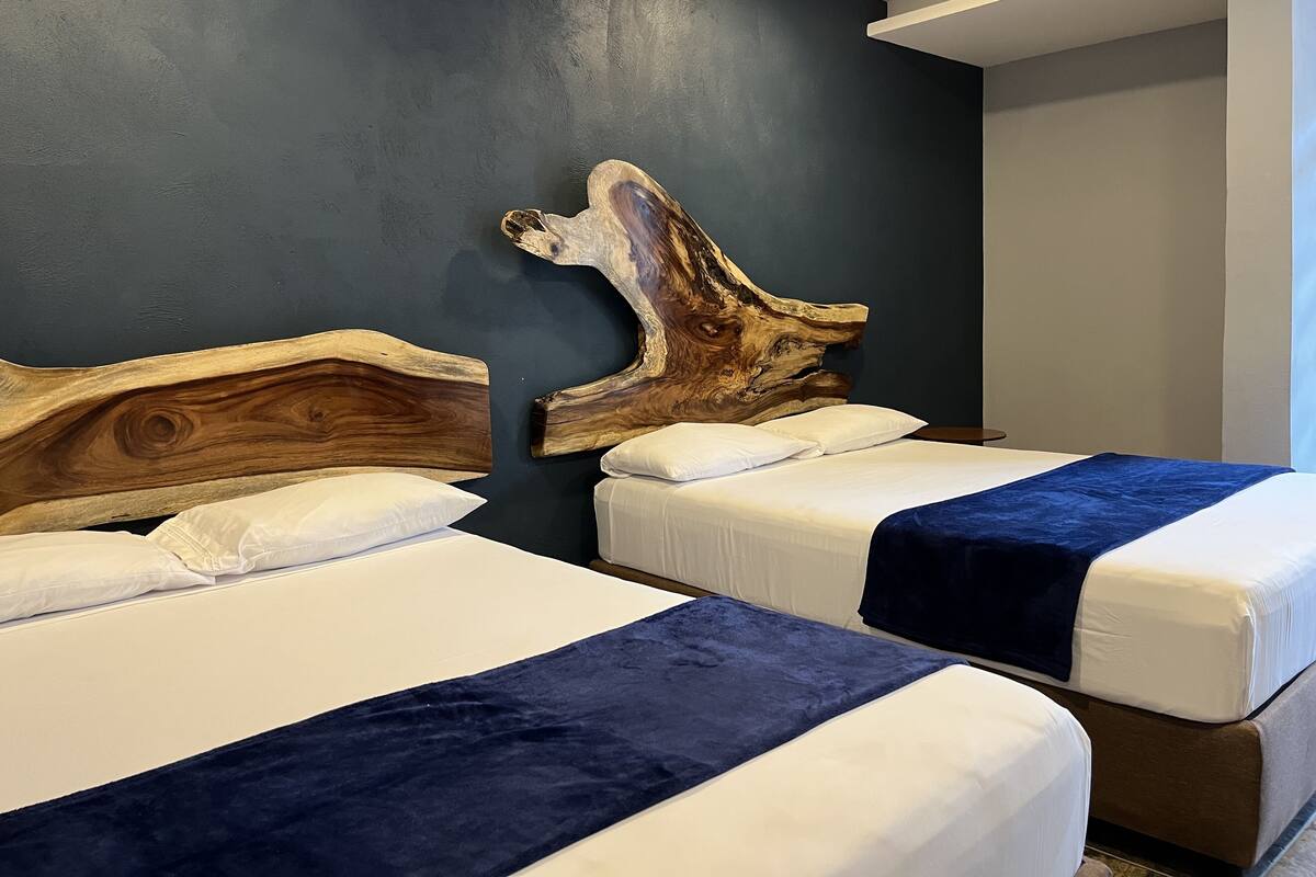 A room with two beds, each with a wooden headboard and white bedding.