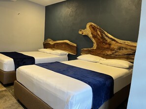 Two single beds with white linens and dark throw blankets, set against a dark grey backdrop.