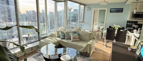 A modern apartment with a city view, a dining area, and a kitchenette.