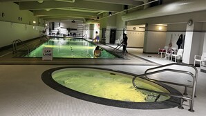 A swimming pool with a lap lane, a changing room, and a seating area with chairs. - Downtown High-rise Condo Amazing View+Pool+Hot Jacuzzi+Sauna+Gym+ free Parking (Vancouver)
