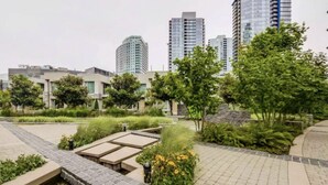 A rooftop garden with a water feature, seating areas, and greenery. - Downtown High-rise Condo Amazing View+Pool+Hot Jacuzzi+Sauna+Gym+ free Parking (Vancouver)