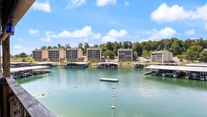 A waterfront property with multiple docked boats, a clear sky, and buildings with large windows and flat roofs. - Turtle Cove –  Lakefront & Indoor Pool! (Village of Four Seasons)