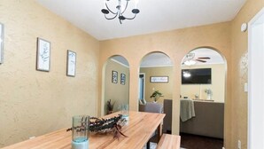 A dining area with a wooden table, benches, and framed artwork on the walls.