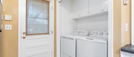 A laundry room with a door, a washing machine, and a dryer.