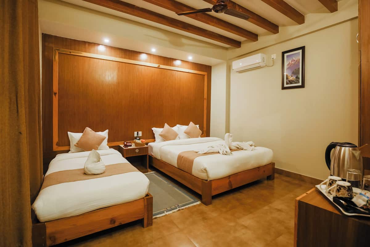Een hotelkamer met twee houten bedden, een houten plafond, een wandairconditioner en een lijst met een foto.