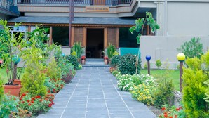 A hotel with a central entrance, multiple balconies, and a garden pathway. - Paradise Boutique Hotel (Pokhara)