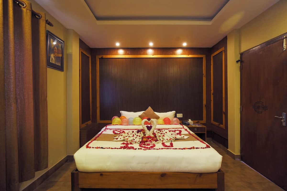 Een hotelkamer met een groot bed, een houten hoofdeinde en een plafondlamp.