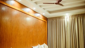 A hotel room with two beds, wooden headboard, ceiling fan, and curtains. - Paradise Boutique Hotel (Pokhara)