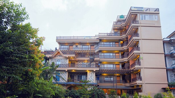 A multi-story hotel with balconies, a garden area, and outdoor seating. - Paradise Boutique Hotel (Pokhara)