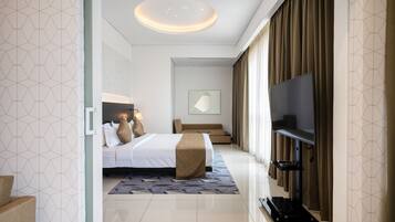 Une chambre d’hôtel moderne dotée d’un grand lit, d’un téléviseur à écran plat, d’un canapé et d’un luminaire fixé au plafond.